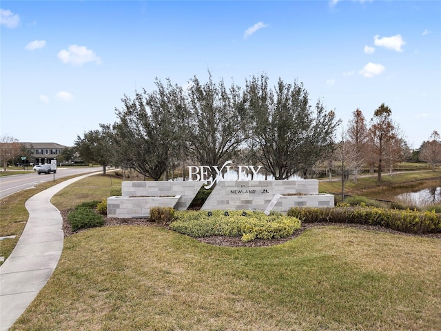 community / neighborhood sign featuring a yard and a water view