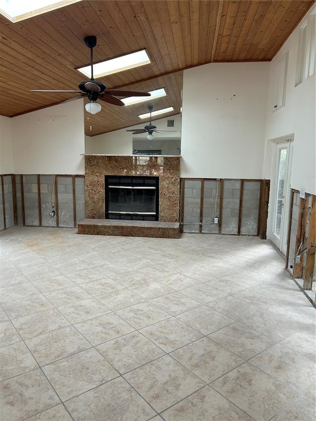 unfurnished living room with wood ceiling, a high end fireplace, vaulted ceiling with skylight, and ceiling fan