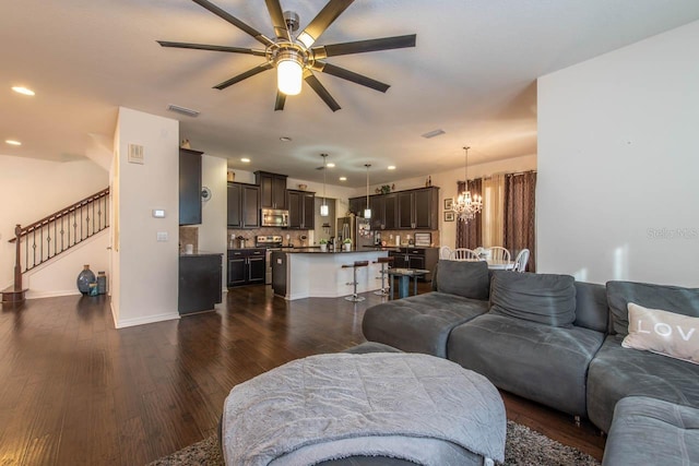 living room featuring dark hardwood / wood-style flooring and ceiling fan with notable chandelier