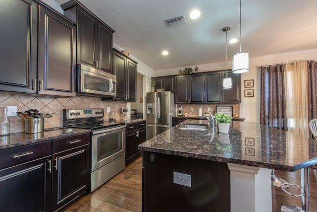 kitchen featuring a breakfast bar, sink, a kitchen island with sink, and appliances with stainless steel finishes