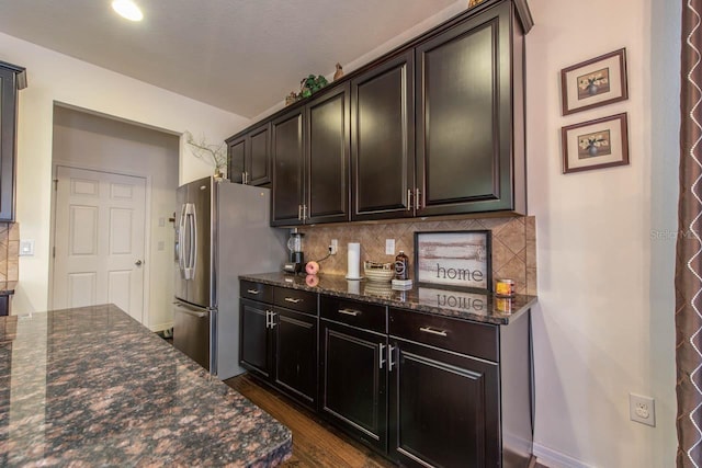 kitchen with decorative backsplash, dark hardwood / wood-style floors, dark stone countertops, and stainless steel refrigerator with ice dispenser