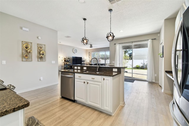 kitchen with dark stone counters, white cabinets, sink, ceiling fan, and appliances with stainless steel finishes