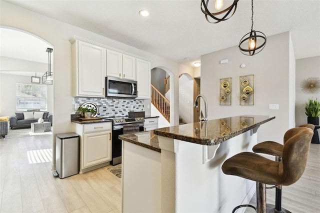 kitchen featuring decorative backsplash, white cabinetry, a breakfast bar, and stainless steel appliances