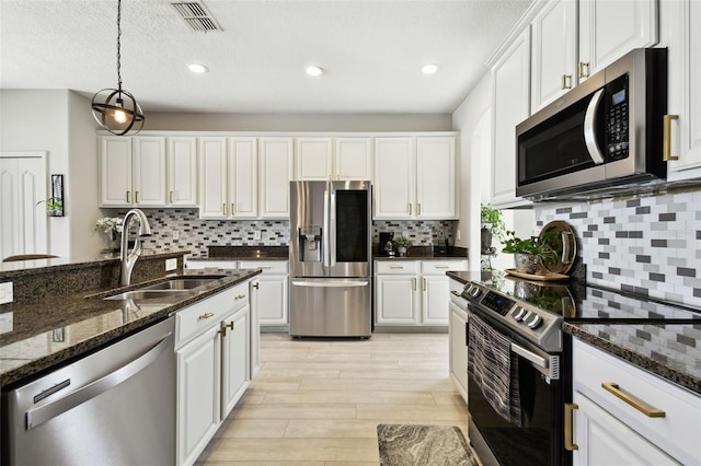 kitchen featuring dark stone countertops, white cabinetry, sink, and appliances with stainless steel finishes