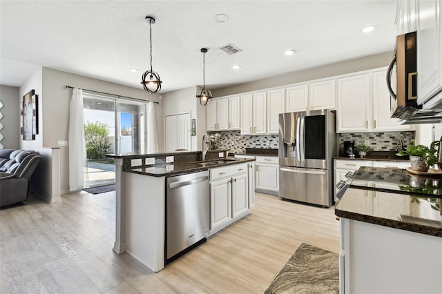 kitchen featuring sink, stainless steel appliances, decorative light fixtures, a center island with sink, and white cabinets