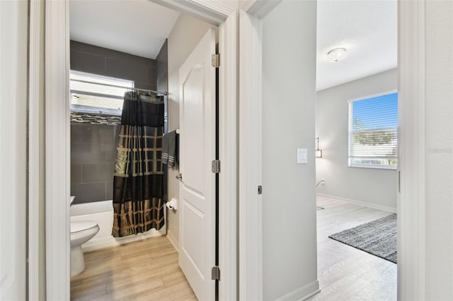 bathroom featuring hardwood / wood-style floors, shower / bath combo, and toilet