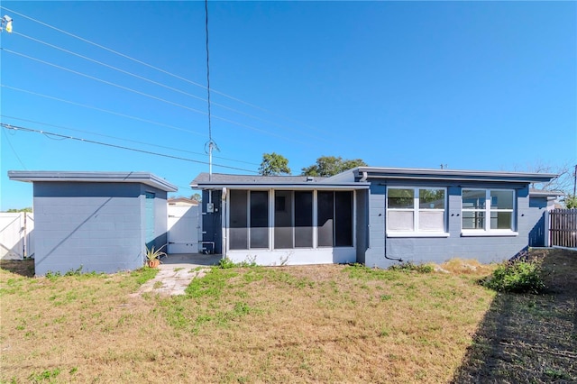 back of property with a lawn and a sunroom