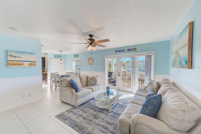 living room featuring ceiling fan, light tile patterned floors, and a textured ceiling