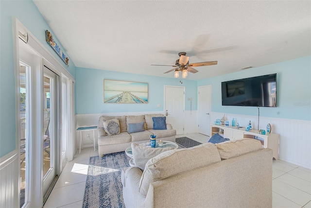 living room featuring ceiling fan, light tile patterned flooring, and a textured ceiling