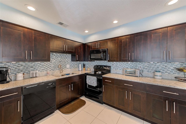 kitchen featuring light stone countertops, tasteful backsplash, dark brown cabinets, sink, and black appliances