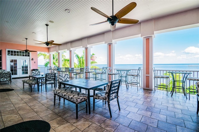 unfurnished dining area featuring french doors, a water view, a wealth of natural light, and ceiling fan