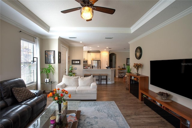 living room featuring a raised ceiling, ornamental molding, ceiling fan, and dark hardwood / wood-style flooring