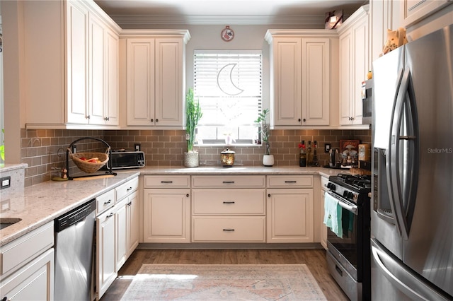 kitchen with light stone counters, tasteful backsplash, crown molding, light hardwood / wood-style flooring, and stainless steel appliances