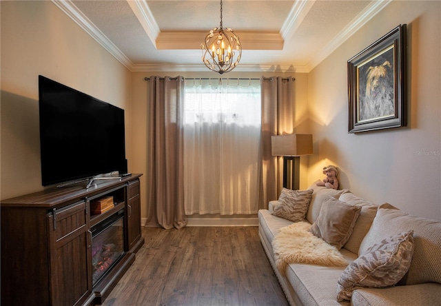 living room featuring hardwood / wood-style flooring, crown molding, a raised ceiling, and an inviting chandelier