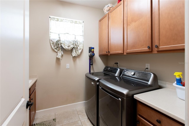 laundry area with washer and dryer, light tile patterned floors, and cabinets