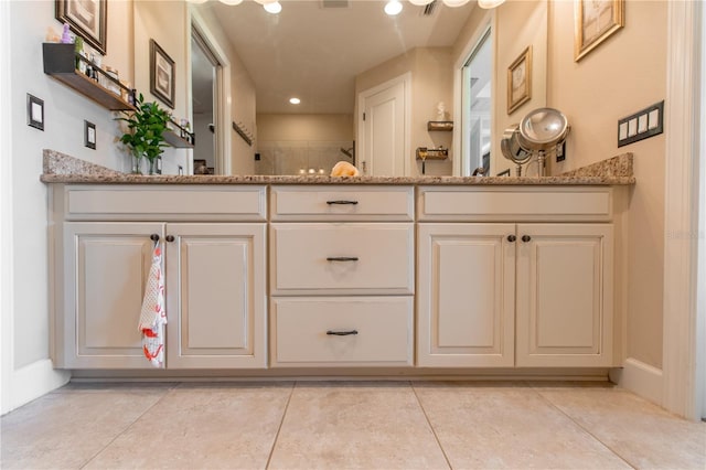 bathroom featuring tile patterned flooring, a shower, and vanity