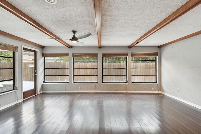 spare room featuring ceiling fan, beamed ceiling, and dark wood-type flooring