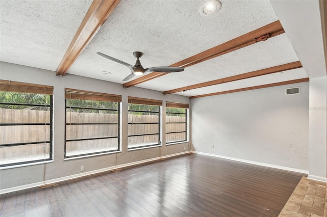 spare room with ceiling fan, dark hardwood / wood-style flooring, beamed ceiling, and a textured ceiling