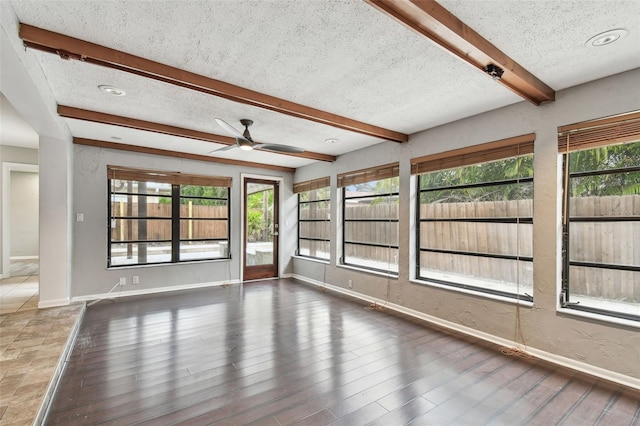 empty room featuring ceiling fan, beam ceiling, dark hardwood / wood-style floors, and a textured ceiling