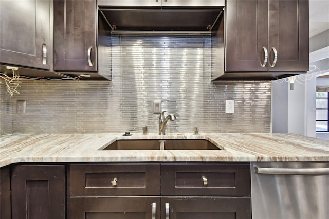 kitchen featuring dark brown cabinetry, dishwasher, sink, light stone counters, and backsplash