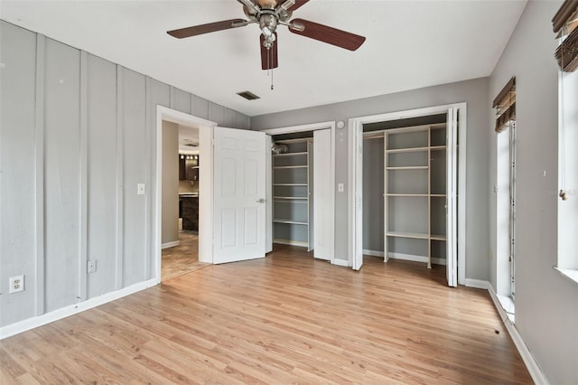 unfurnished bedroom with multiple closets, ceiling fan, and light wood-type flooring