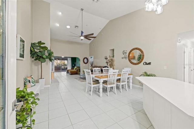 tiled dining area with ceiling fan and high vaulted ceiling