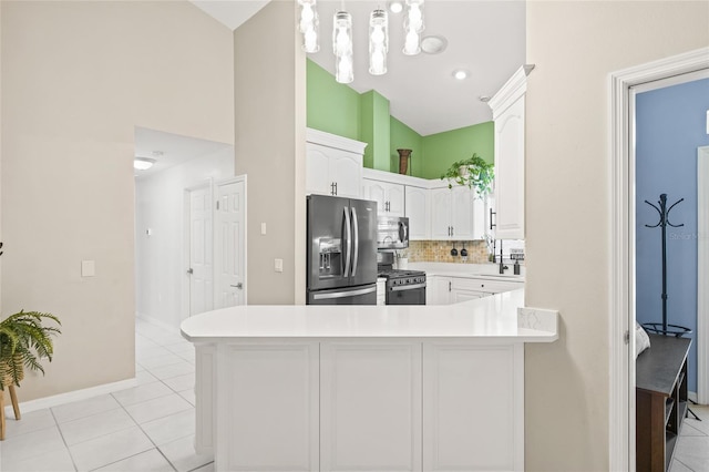 kitchen featuring kitchen peninsula, pendant lighting, tasteful backsplash, white cabinetry, and appliances with stainless steel finishes