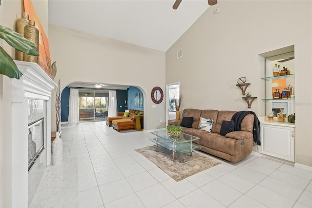 living room with a premium fireplace, high vaulted ceiling, ceiling fan, and light tile patterned flooring