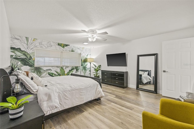 bedroom with light wood-type flooring, a textured ceiling, and ceiling fan