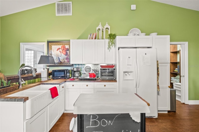 kitchen with lofted ceiling, white cabinets, tasteful backsplash, and white fridge with ice dispenser