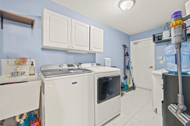 clothes washing area with sink, a textured ceiling, cabinets, and independent washer and dryer