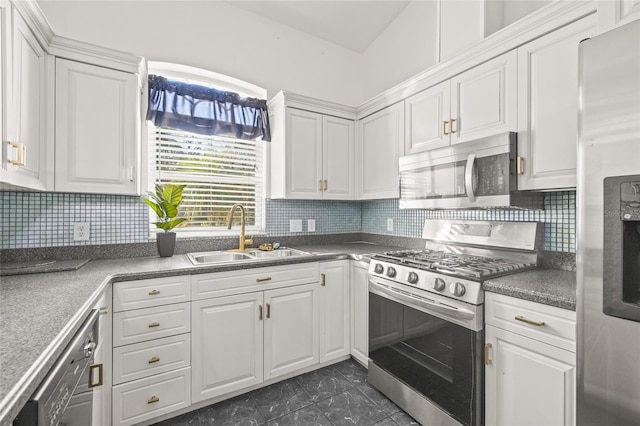 kitchen with appliances with stainless steel finishes, dark tile patterned flooring, decorative backsplash, sink, and white cabinetry