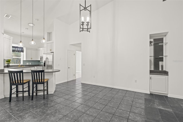 kitchen with white cabinetry, a kitchen breakfast bar, backsplash, high vaulted ceiling, and pendant lighting