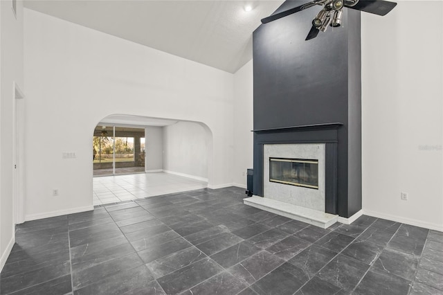 unfurnished living room with ceiling fan, vaulted ceiling, and a fireplace