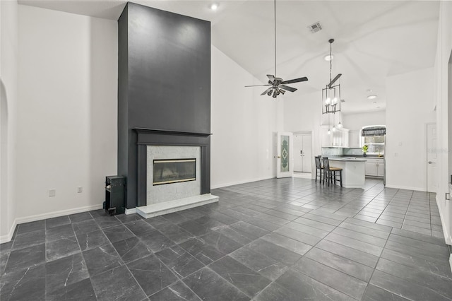 unfurnished living room featuring a high end fireplace, high vaulted ceiling, and ceiling fan