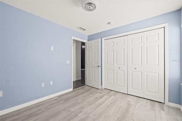 unfurnished bedroom featuring light hardwood / wood-style floors, a closet, and a textured ceiling