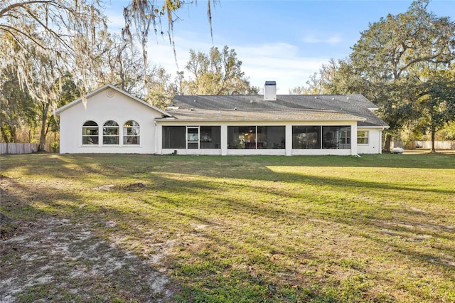 rear view of house with a yard and a sunroom