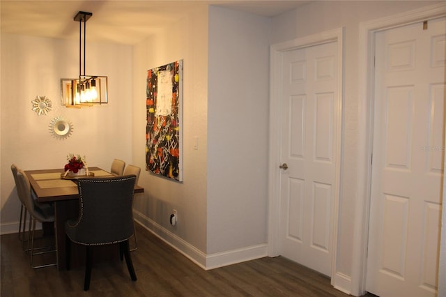 dining space with dark wood-type flooring and an inviting chandelier