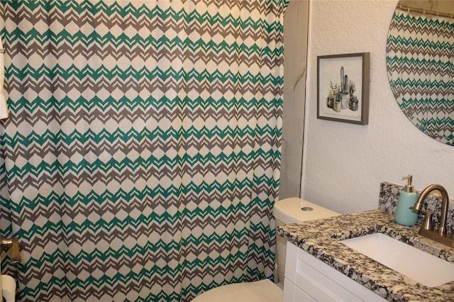 bathroom featuring a shower with shower curtain, vanity, and toilet