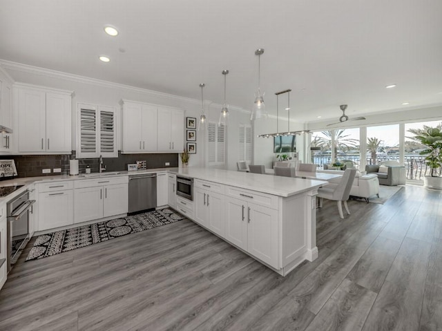 kitchen with hanging light fixtures, kitchen peninsula, ceiling fan, white cabinetry, and stainless steel appliances