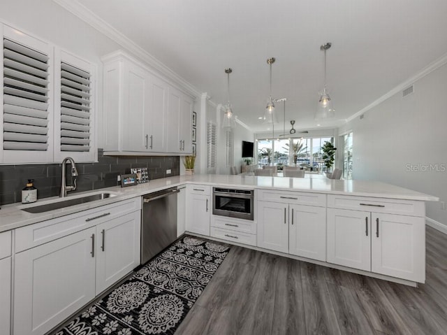 kitchen with kitchen peninsula, sink, pendant lighting, dishwasher, and white cabinets