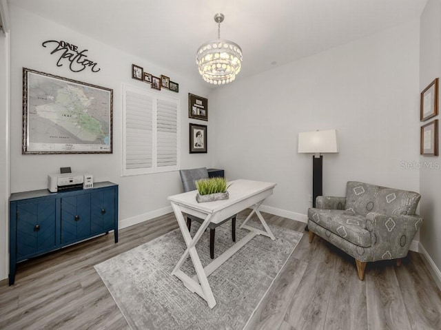 home office with a notable chandelier and light hardwood / wood-style flooring