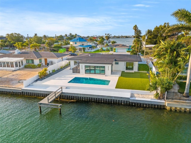 back of property with a water view, a patio, and a lawn