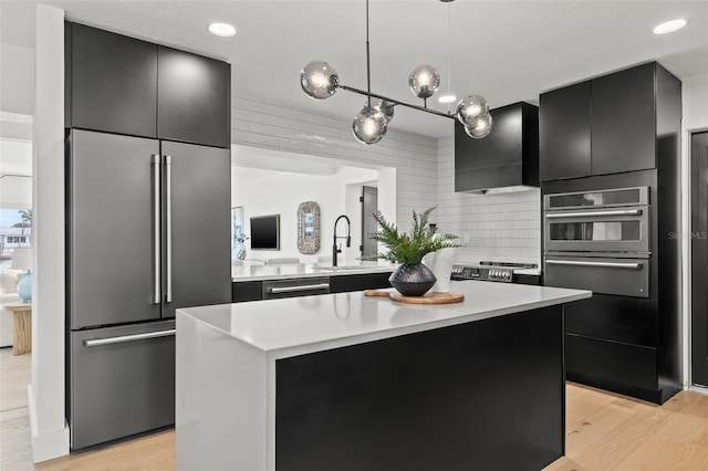 kitchen with appliances with stainless steel finishes, pendant lighting, sink, a center island, and light hardwood / wood-style flooring