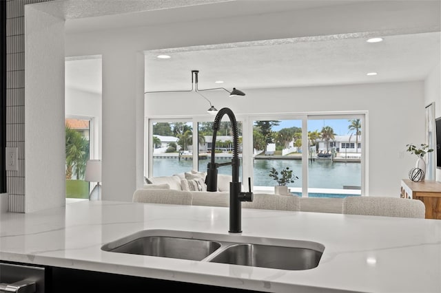 kitchen with plenty of natural light, light stone countertops, sink, and a textured ceiling