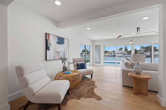 sitting room with a water view, beam ceiling, and light hardwood / wood-style flooring