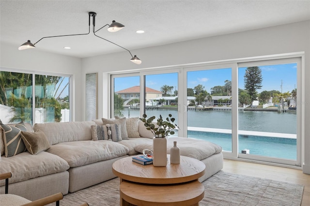 living room featuring a water view, a textured ceiling, and light wood-type flooring