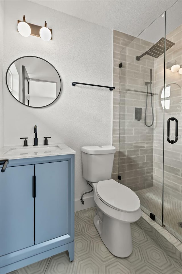 bathroom with tile patterned flooring, vanity, toilet, and walk in shower