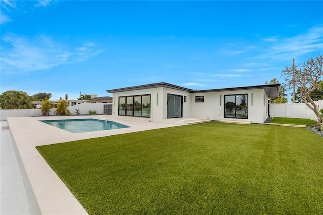 rear view of house with a fenced in pool, a lawn, and a patio area