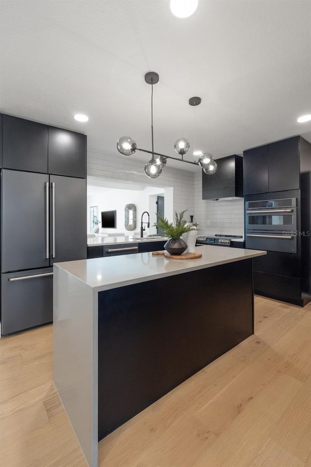 kitchen featuring light hardwood / wood-style flooring, hanging light fixtures, a kitchen island, and built in refrigerator